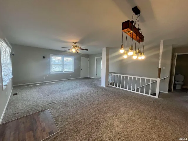 a view of an empty room and chandelier fan
