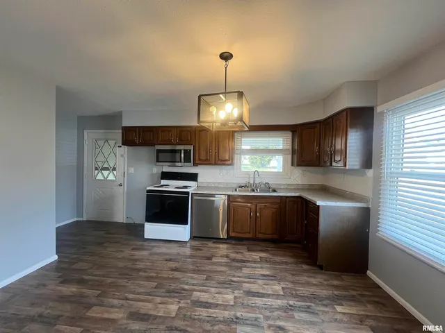a kitchen with granite countertop stainless steel appliances and wooden floor