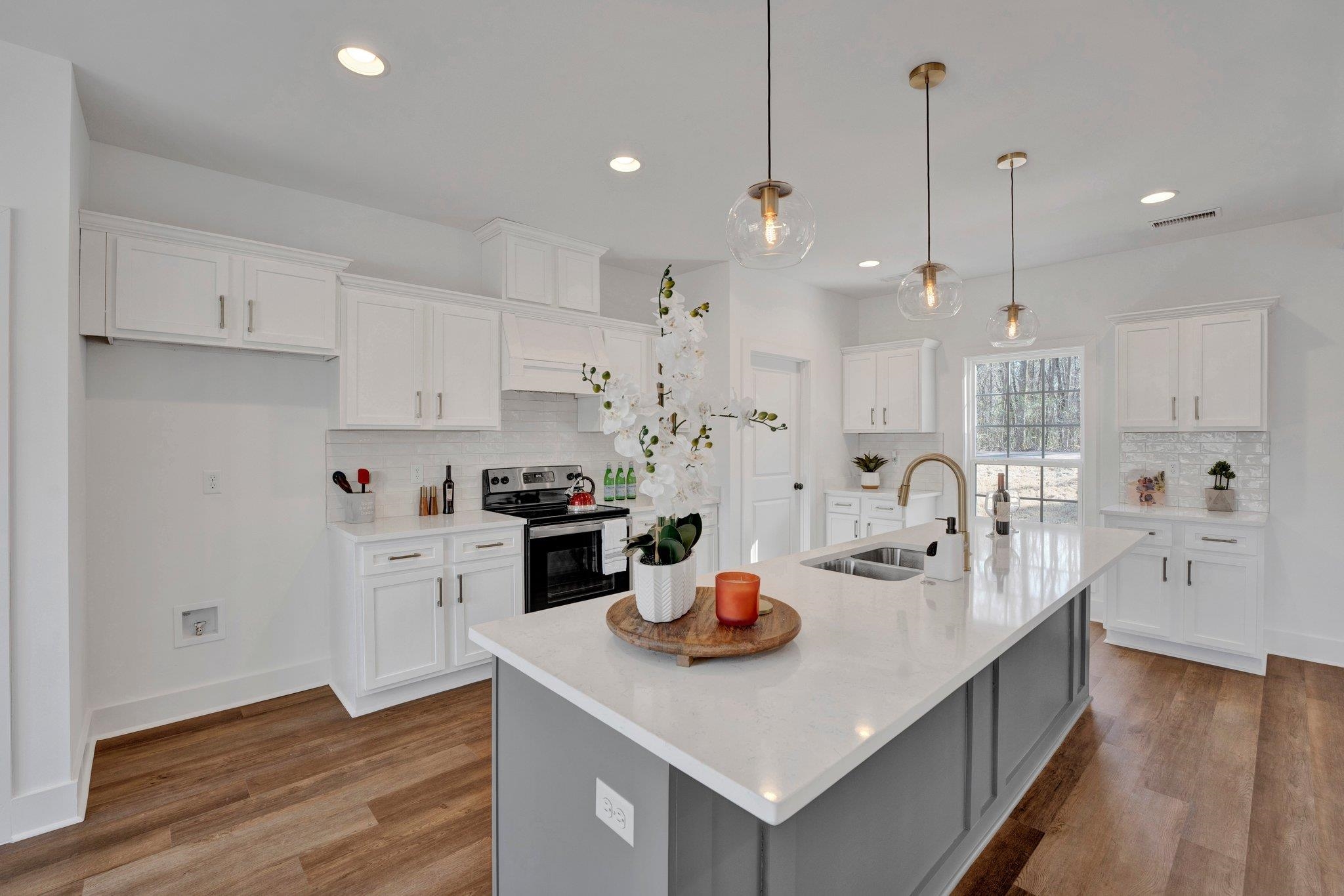 5702 Spring Lake Road Memphis, TN 38135 - Photo 12 of 38 a kitchen with stainless steel appliances granite countertop a sink a stove and white cabinets with wooden floor