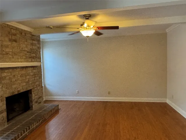 a view of an empty room with wooden floor and a fireplace