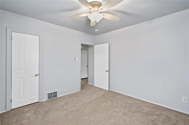 an empty room with chandelier fan and windows