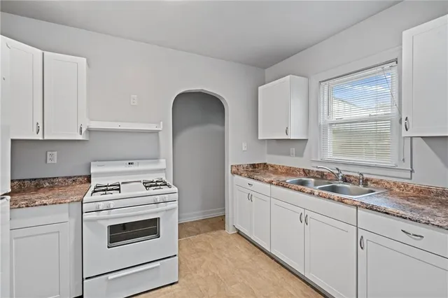 a kitchen with granite countertop a stove sink and cabinets