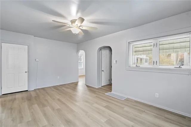 an empty room with wooden floor fan and windows