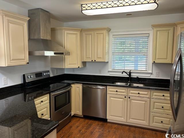 2477 Pleasant Grove Road Loris, SC 29569 - Photo 2 of 25 Kitchen with stainless steel appliances, wall chimney exhaust hood, dark wood-style flooring, cream cabinets, and dark stone counters