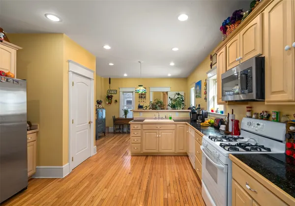a large kitchen with stainless steel appliances granite countertop a lot of counter space and wooden floor