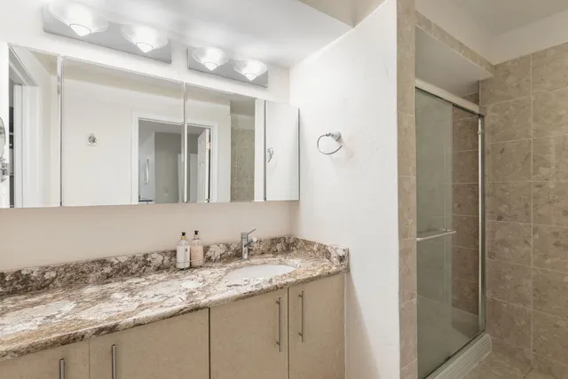 a bathroom with a granite countertop sink and a mirror