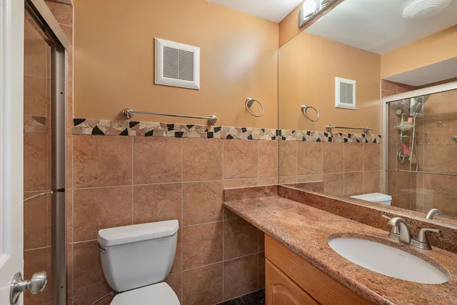 a bathroom with a granite countertop sink toilet and shower