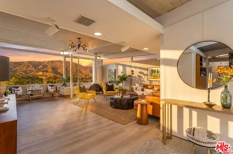 a living room with furniture kitchen view and a large window
