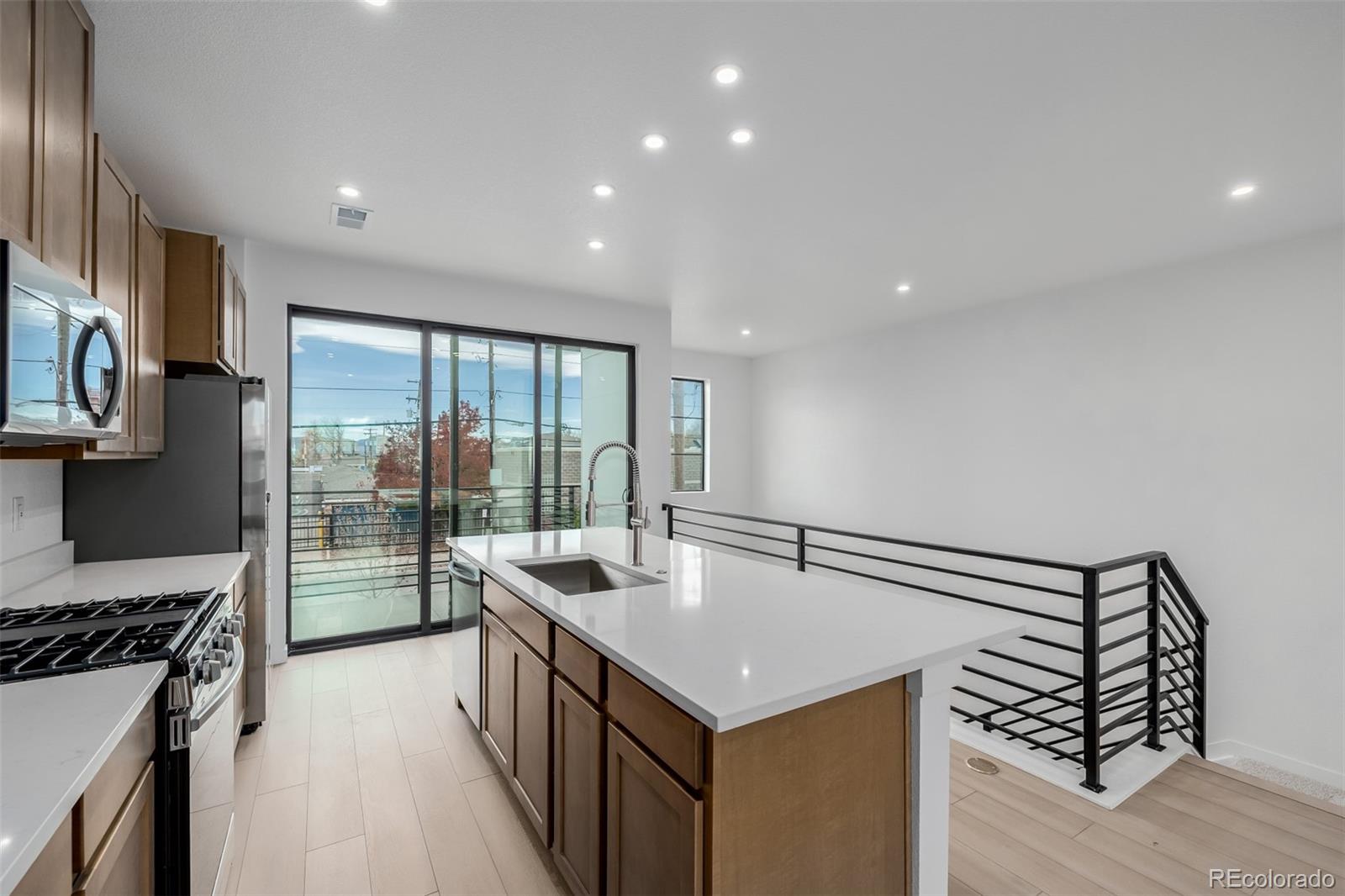 2076 South Holly Street, Unit 2 Denver, CO 80222 - Photo 5 of 22 a kitchen with kitchen island a sink a stove and a refrigerator