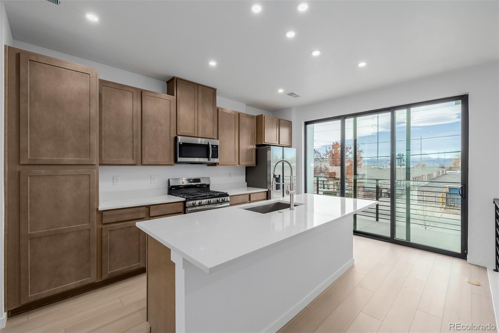 2076 South Holly Street, Unit 2 Denver, CO 80222 - Photo 6 of 22 a kitchen with kitchen island a counter top space appliances and cabinets