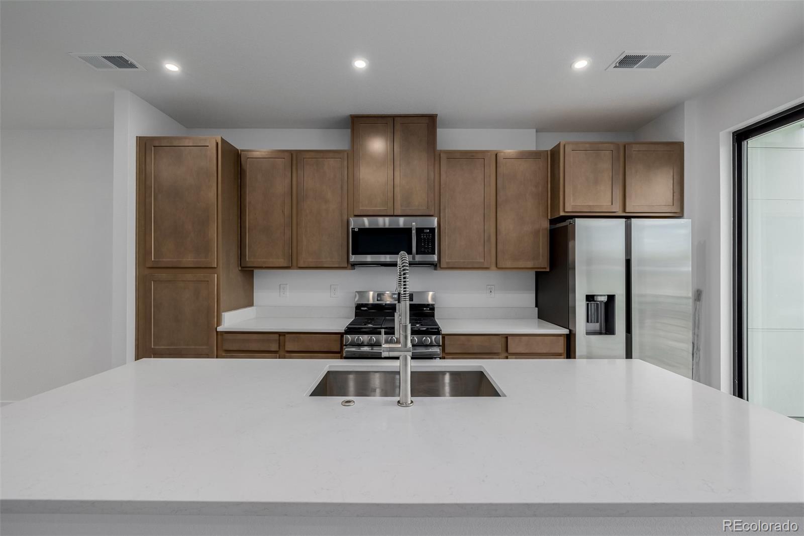 2076 South Holly Street, Unit 2 Denver, CO 80222 - Photo 6 of 24 a kitchen with stainless steel appliances a refrigerator a stove a sink a washer and dryer
