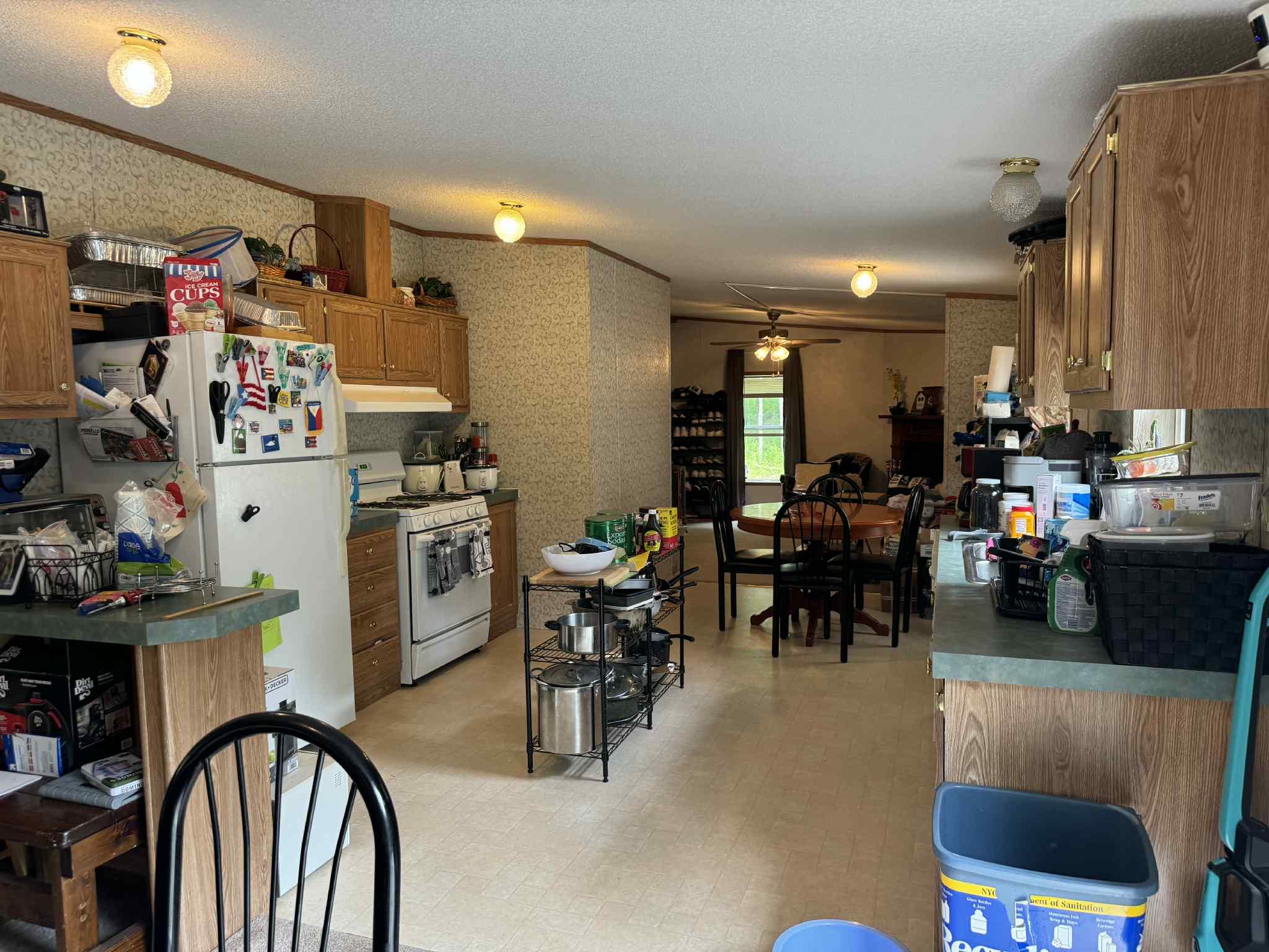 108 Todd Road Woodbourne, NY 12788 - Photo 7 of 13 Kitchen featuring wallpapered walls, brown cabinetry, white appliances, a ceiling fan, and under cabinet range hood