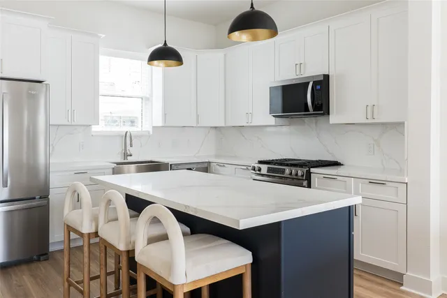 a kitchen with kitchen island a counter space a sink appliances and cabinets