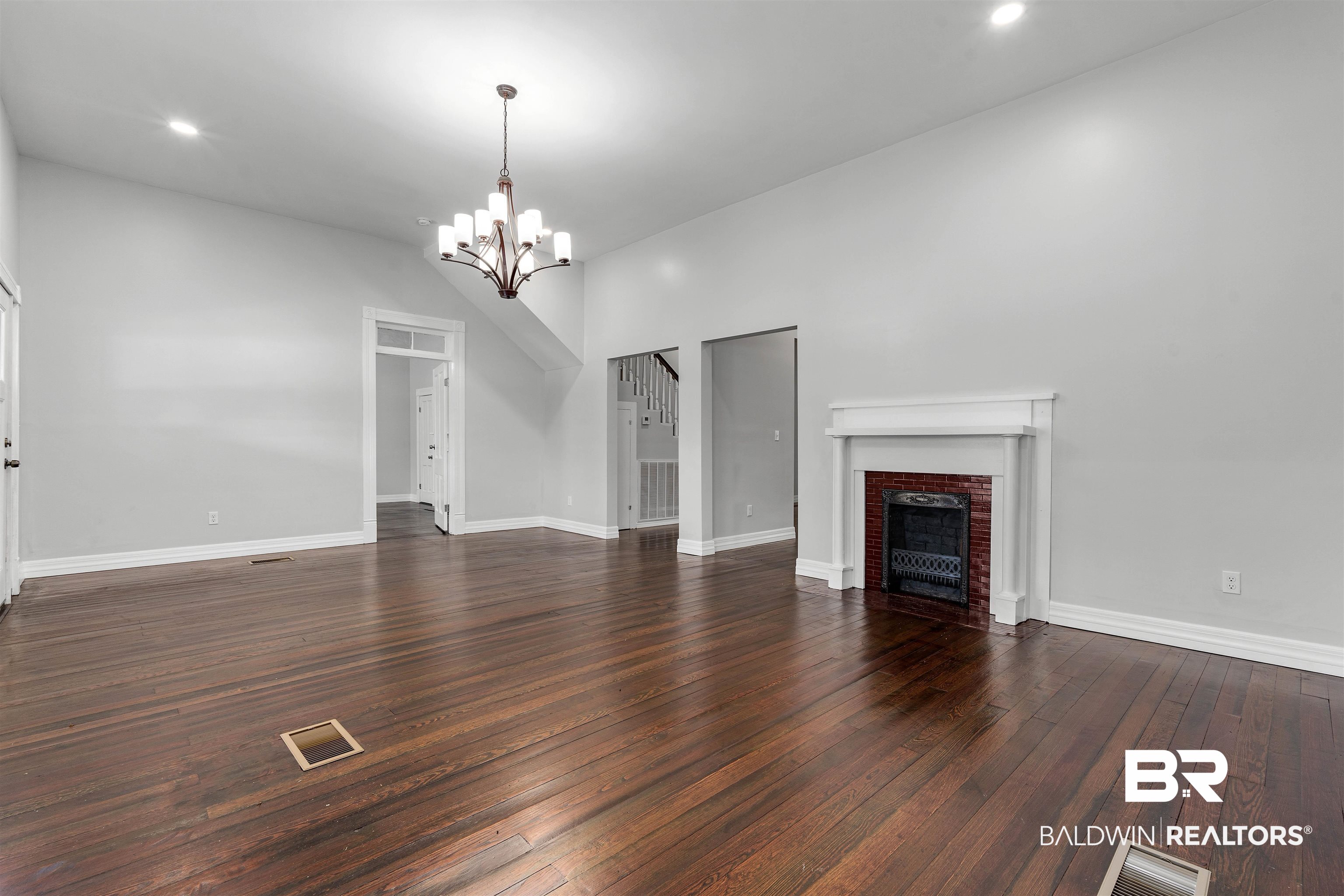 407 East 2nd Street Bay Minette, AL 36507 - Photo 6 of 40 Unfurnished living room featuring dark wood-type flooring, a fireplace, a chandelier, vaulted ceiling, and recessed lighting