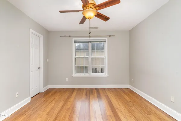 a view of an empty room with window and wooden floor