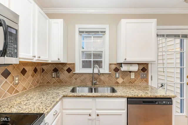 a kitchen with granite countertop a sink a window and cabinets