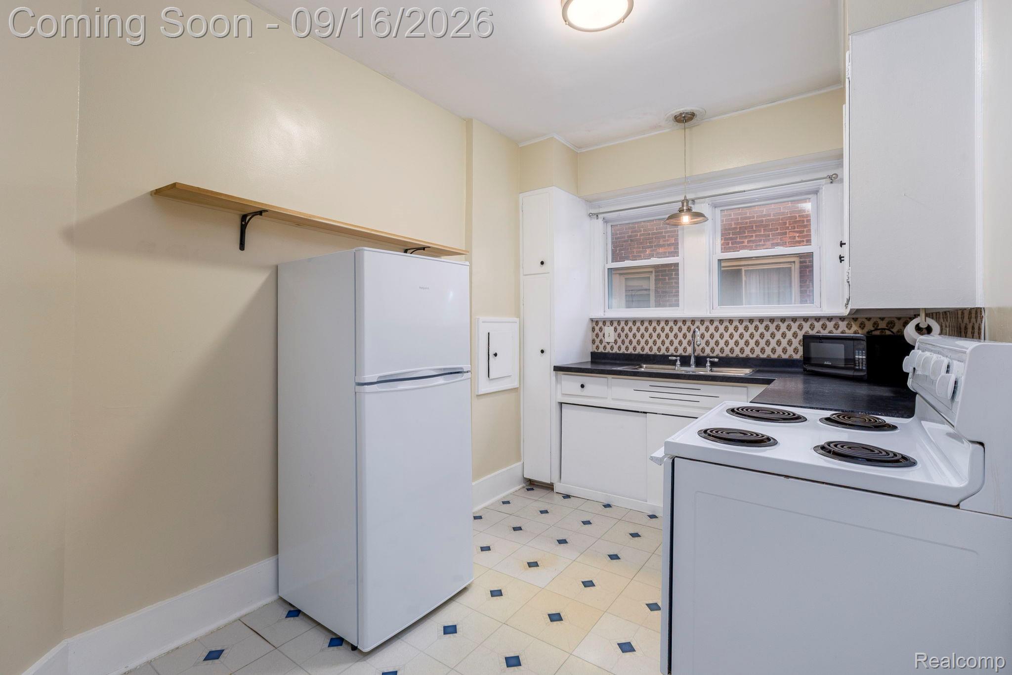 999 Nottingham Road Grosse Pointe, MI 48230 - Photo 15 of 30 Kitchen featuring patterned tile flooring, white cabinetry, dark countertops, and a tiled backsplash