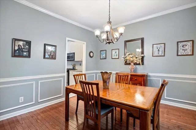 a dining room with wooden floor a chandelier a wooden table and chairs