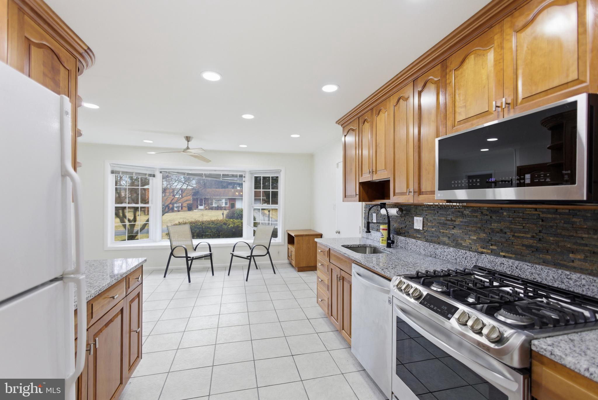 14717 Flintstone Lane Silver Spring, MD 20905 - Photo 9 of 32 a kitchen with stainless steel appliances granite countertop a stove a sink and a microwave