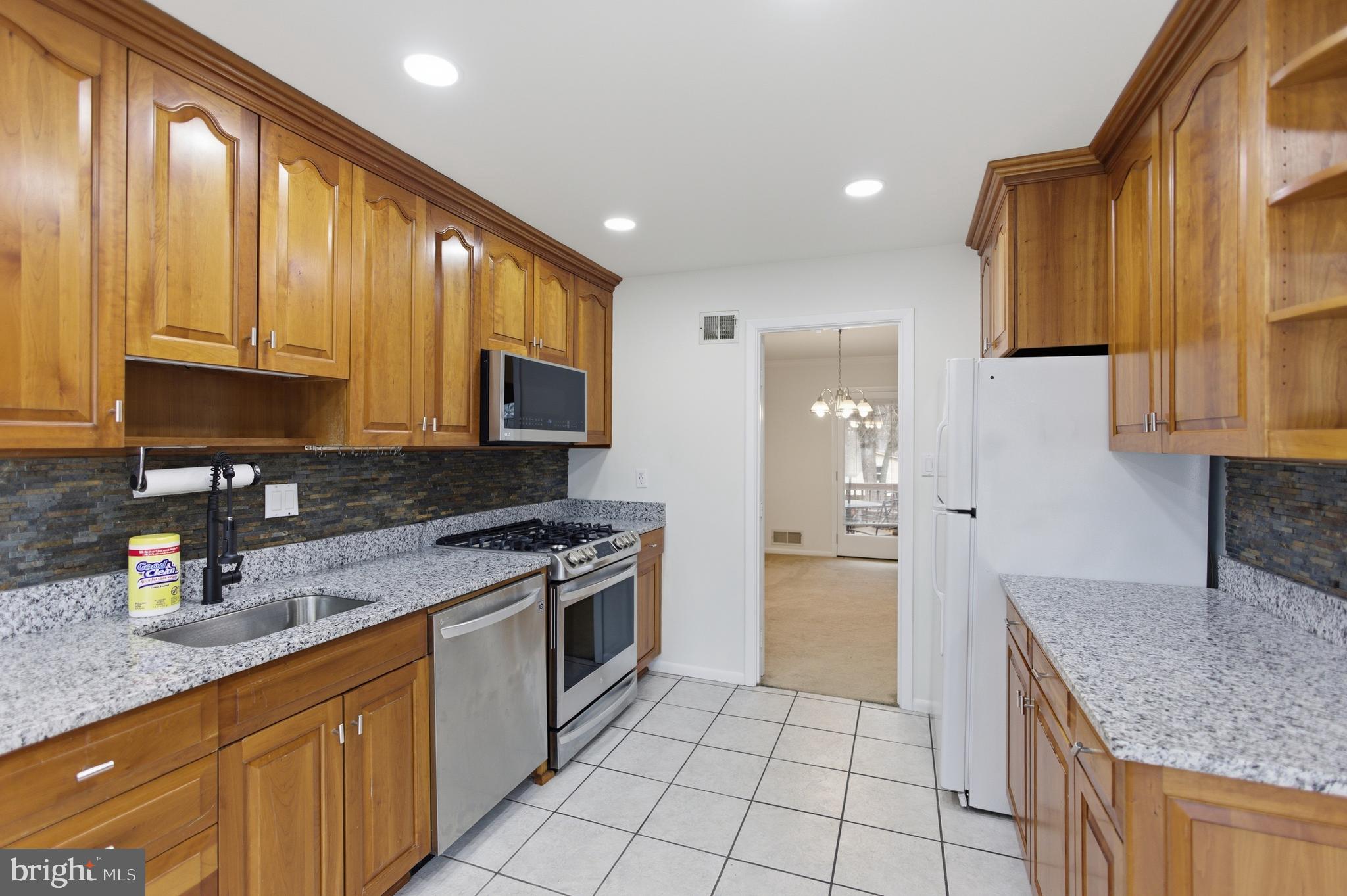 14717 Flintstone Lane Silver Spring, MD 20905 - Photo 10 of 32 a kitchen with stainless steel appliances granite countertop a stove a sink and a microwave