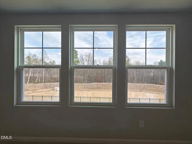a view of an empty room with wooden floor and windows