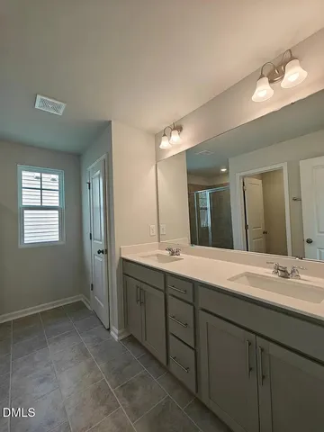 a spacious bathroom with a double vanity sink mirror and next to a window