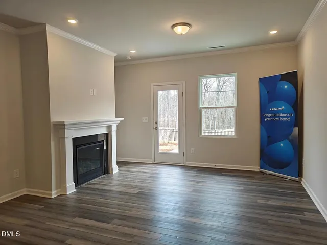 an empty room with wooden floor fireplace and windows