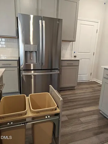 a view of a refrigerator in kitchen and an empty room