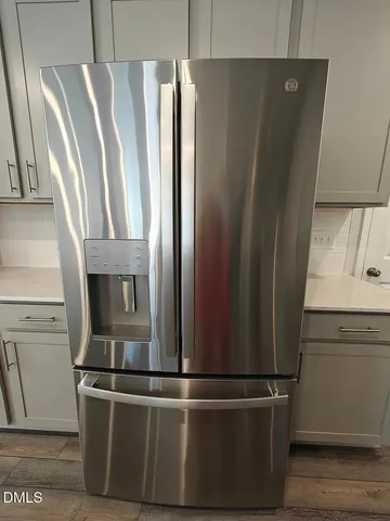a view of a refrigerator in kitchen and an empty room