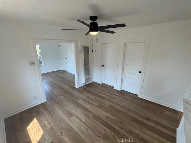 an empty room with wooden floor ceiling fan and window