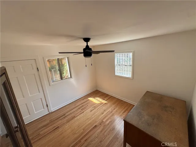 a view of empty room with wooden floor and fan