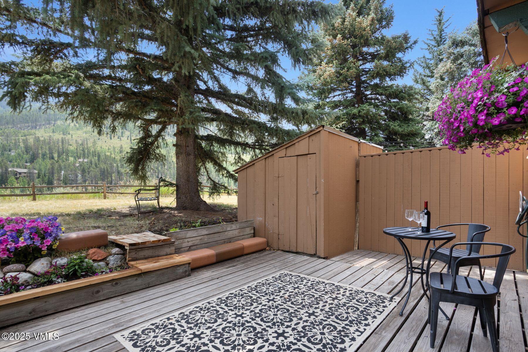 2456 Chamonix Lane, Unit B3 Vail, CO 81657 - Photo 11 of 29 a backyard of a house with table and chairs with wooden fence and plants