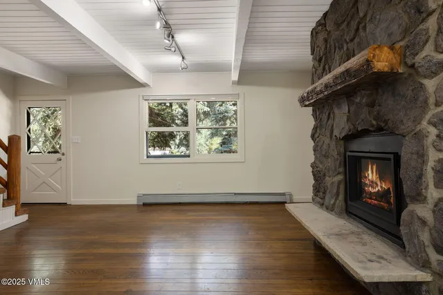 a view of an empty room with wooden floor and a fireplace