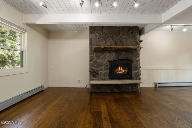 an empty room with wooden floor fireplace and windows