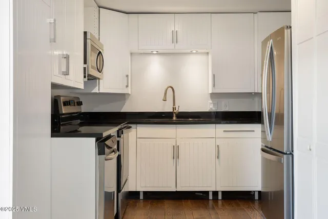 a backyard of a house with table and chairs with wooden fence and plants