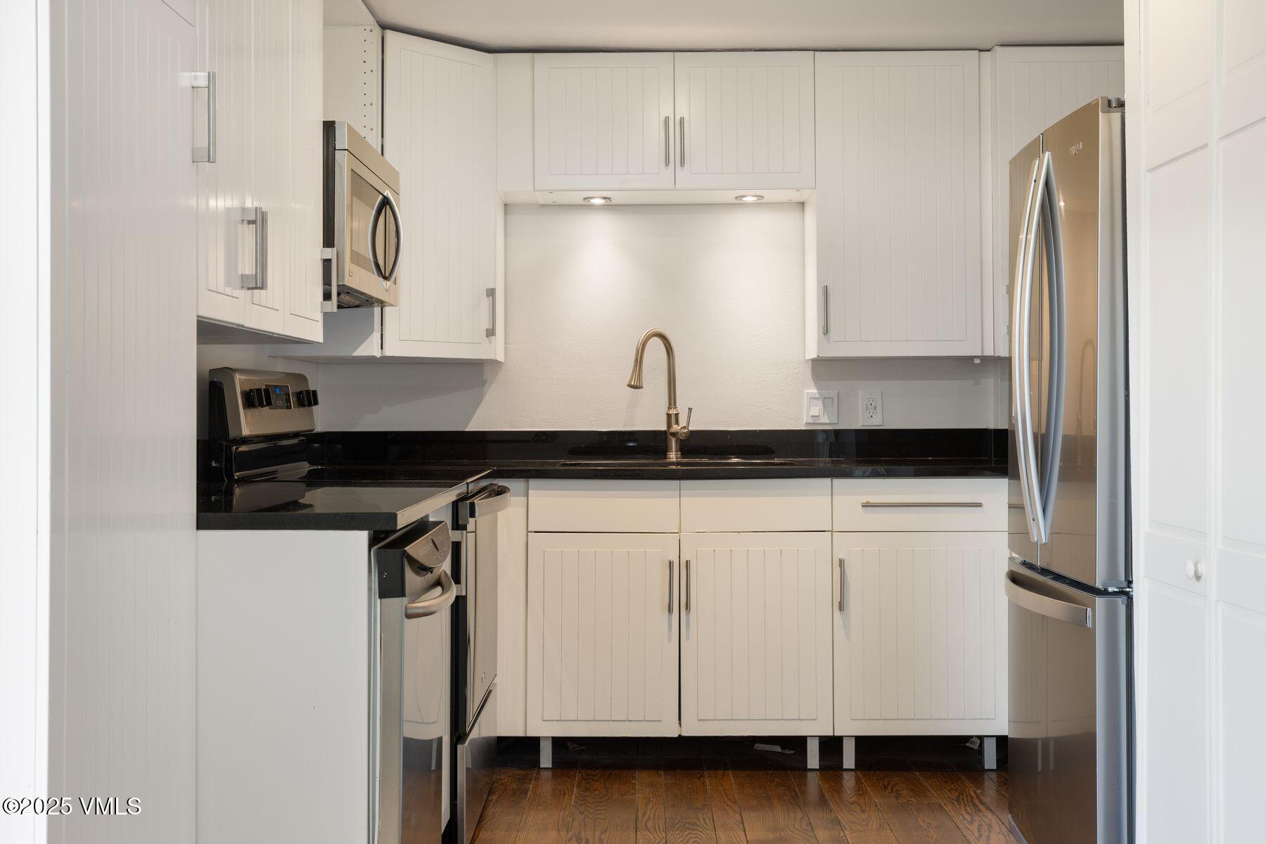 2456 Chamonix Lane, Unit B3 Vail, CO 81657 - Photo 10 of 29 a kitchen with granite countertop white cabinets white stainless steel appliances and a sink