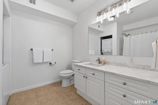 a bathroom with a granite countertop sink mirror and toilet