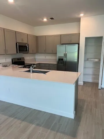 a kitchen with stainless steel appliances a sink a microwave a refrigerator and cabinets