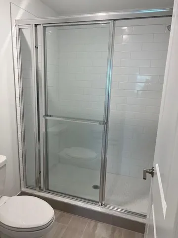 a bathroom with a shower a toilet and a glass door shower