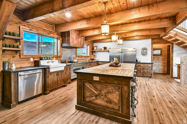 544 East 600 North, Unit 1 Joseph, UT 84739 - Photo 10 of 65 Open-concept kitchen featuring wood-finish flooring, exposed wood beam ceiling, custom wood cabinetry, a central island with bar seating, and stainless steel appliances