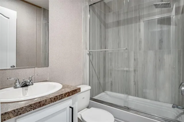 a bathroom with a granite countertop sink vanity mirror and toilet