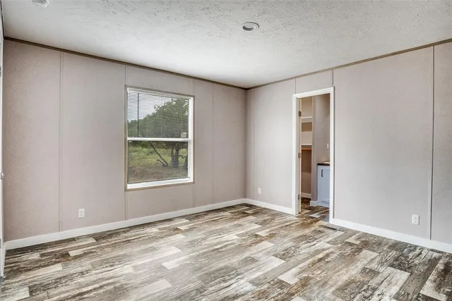 a view of an empty room with window and wooden floor
