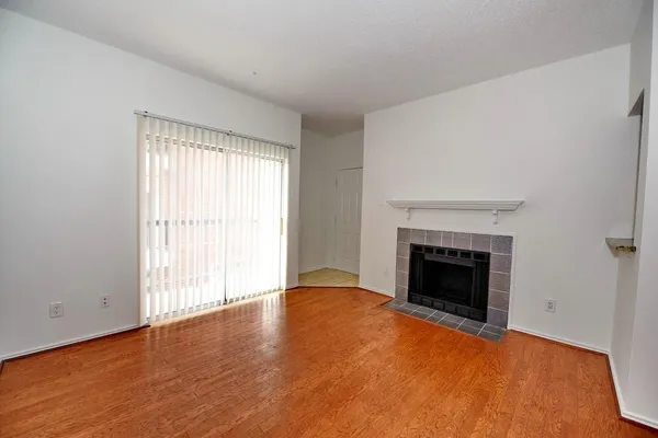 a view of empty room with wooden floor fireplace and window