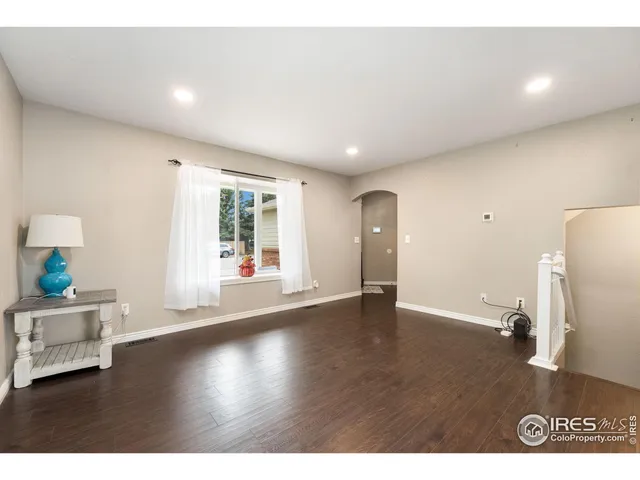 a view of an empty room with window and wooden floor