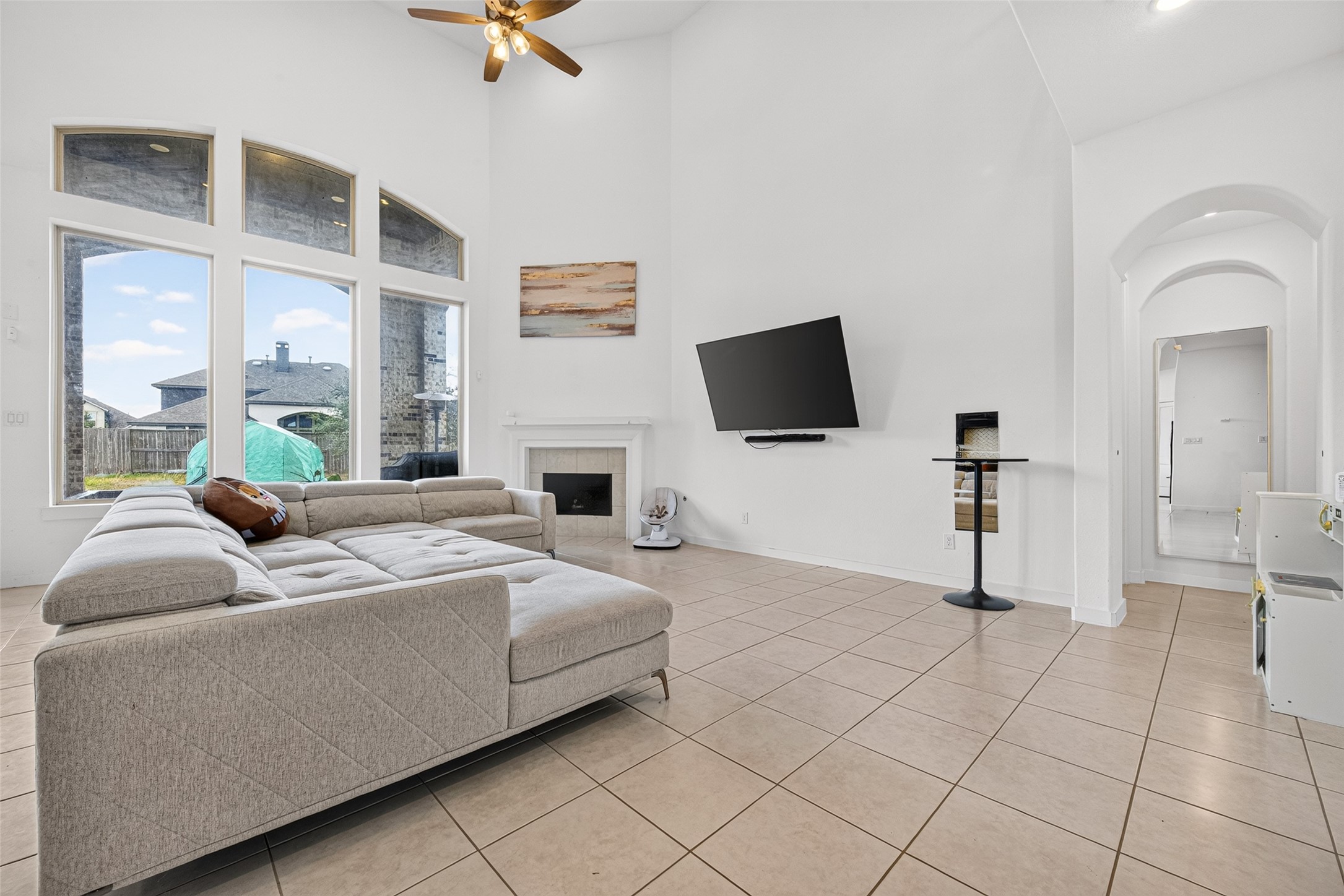 10114 Brush Way Rosharon, TX 77583 - Photo 13 of 50 Spacious living room with high ceilings, abundant natural light from large windows, and a cozy fireplace, perfect for relaxation and entertainment.