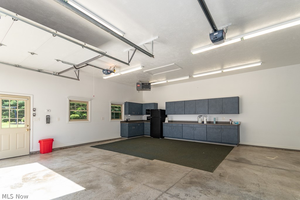 7710 Brakeman Road Painesville, OH 44077 - Photo 34 of 34 Garage with black refrigerator and a garage door opener