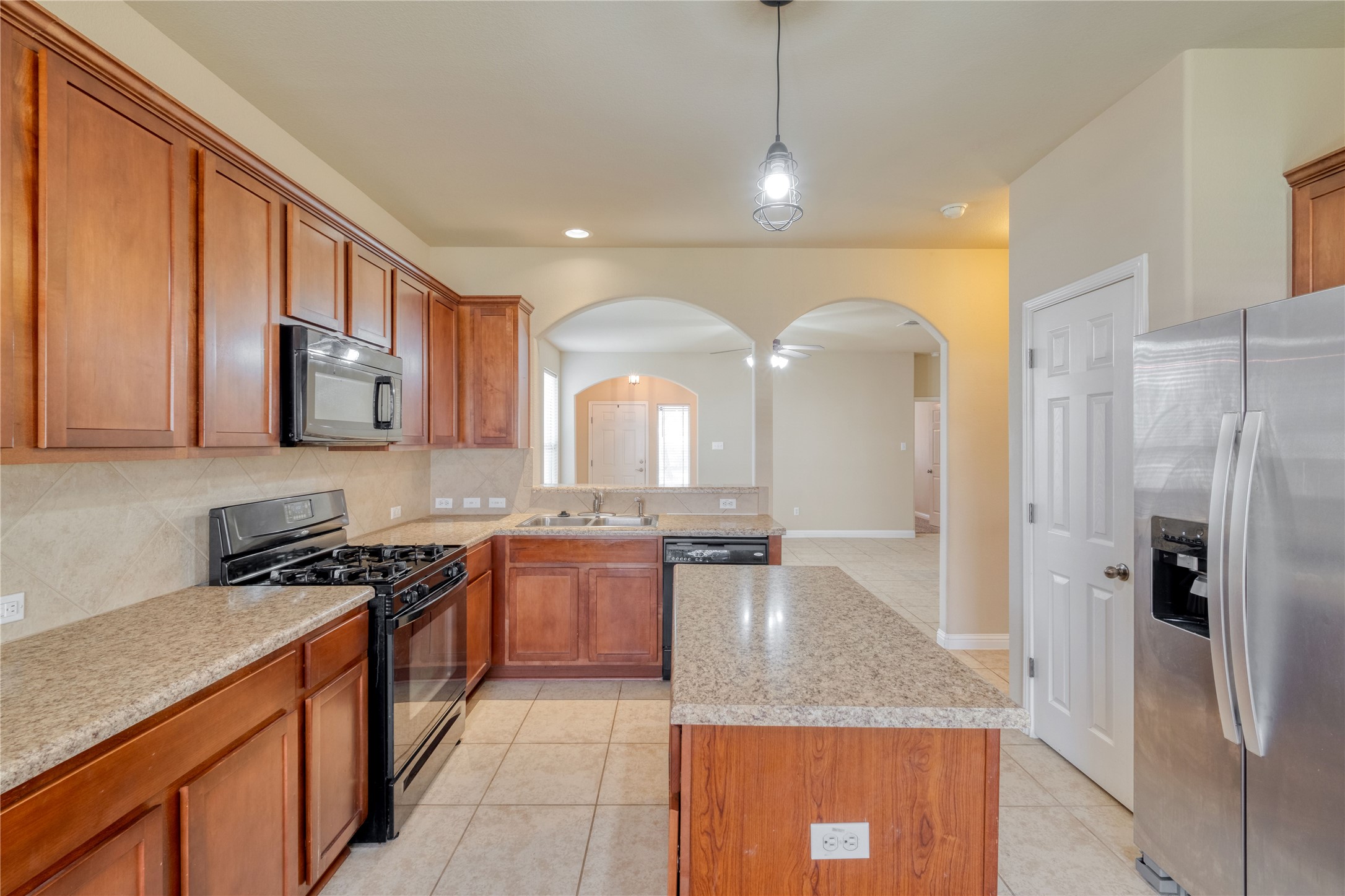 194 Cold Springs Spring Buda, TX 78610 - Photo 7 of 17 Kitchen with black appliances, wood finish cabinets, and light tile patterned flooring