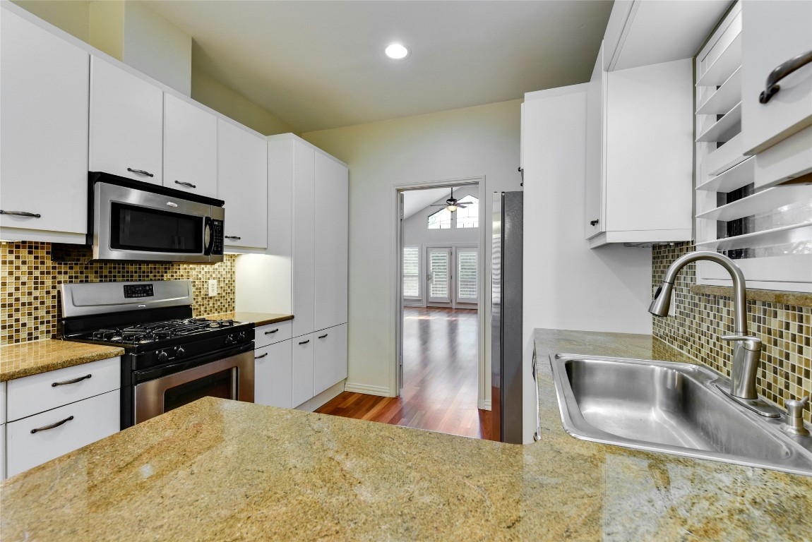 3509 Fawn Trail Austin, TX 78746 - Photo 13 of 30 a kitchen with stainless steel appliances a stove a sink a microwave a refrigerator white cabinets and wooden floor