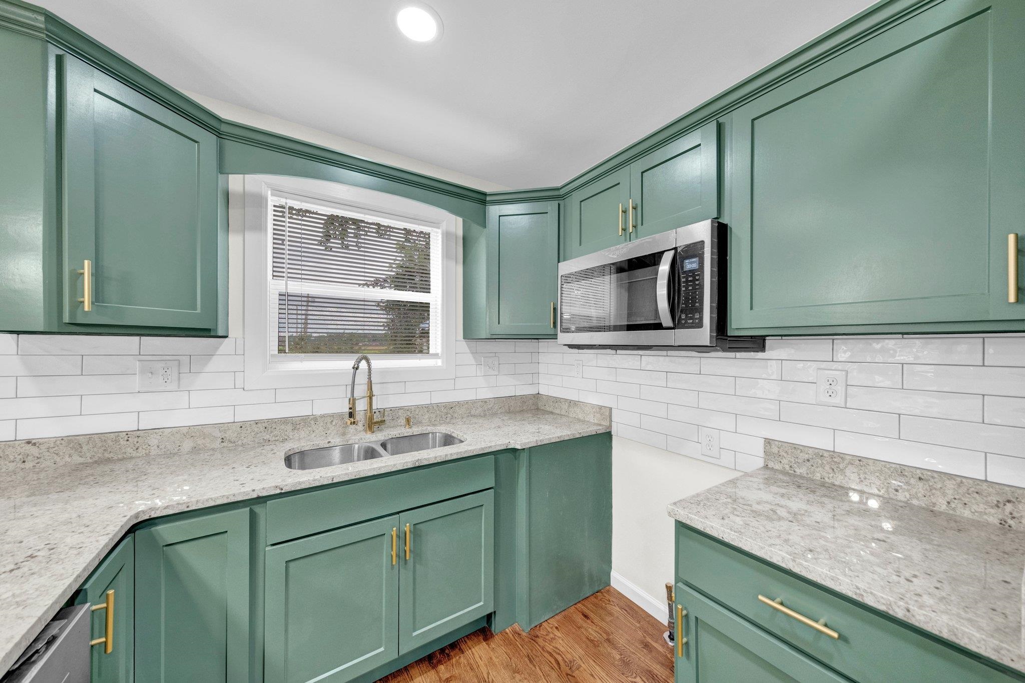 6681 Raleigh Millington Road Millington, TN 38053 - Photo 12 of 28 Kitchen featuring appliances with stainless steel finishes, decorative backsplash, light wood finished floors, green cabinets, and light stone countertops