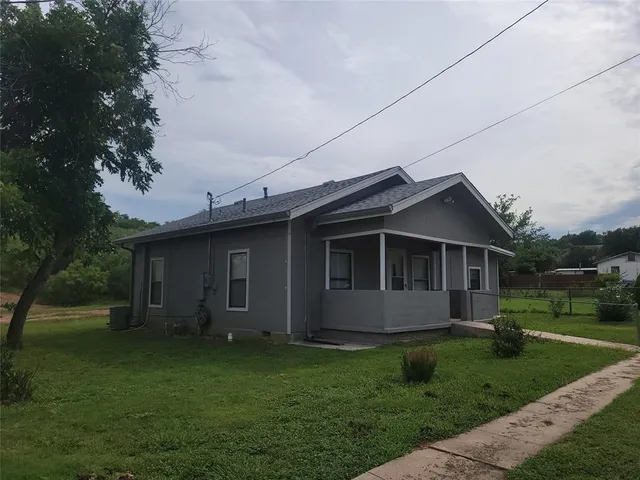 a view of a yard in front of a house with large tree